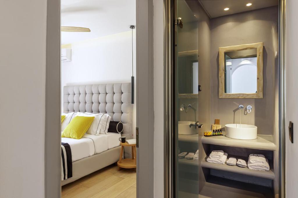a bedroom with a bed and a sink and a mirror at Kalisti Hotel & Suites in Fira