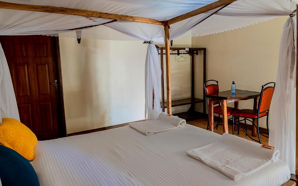 a bedroom with a canopy bed with a table and chairs at Kimberly ecolodges narok in Narok