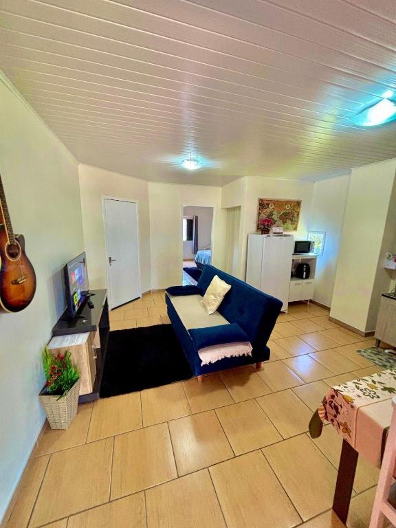 a living room with a blue couch and a kitchen at Acomodação no centro de Tangará in Tangará
