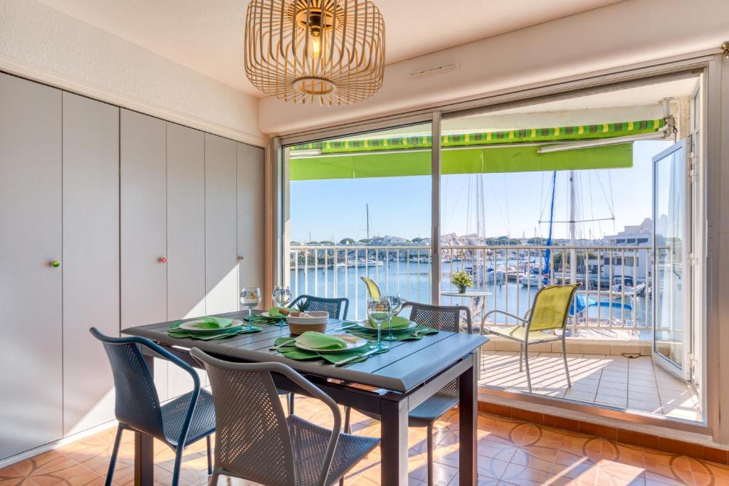 une salle à manger avec une table et des chaises et un balcon dans l'établissement Marina Port Camargue, au Grau-du-Roi