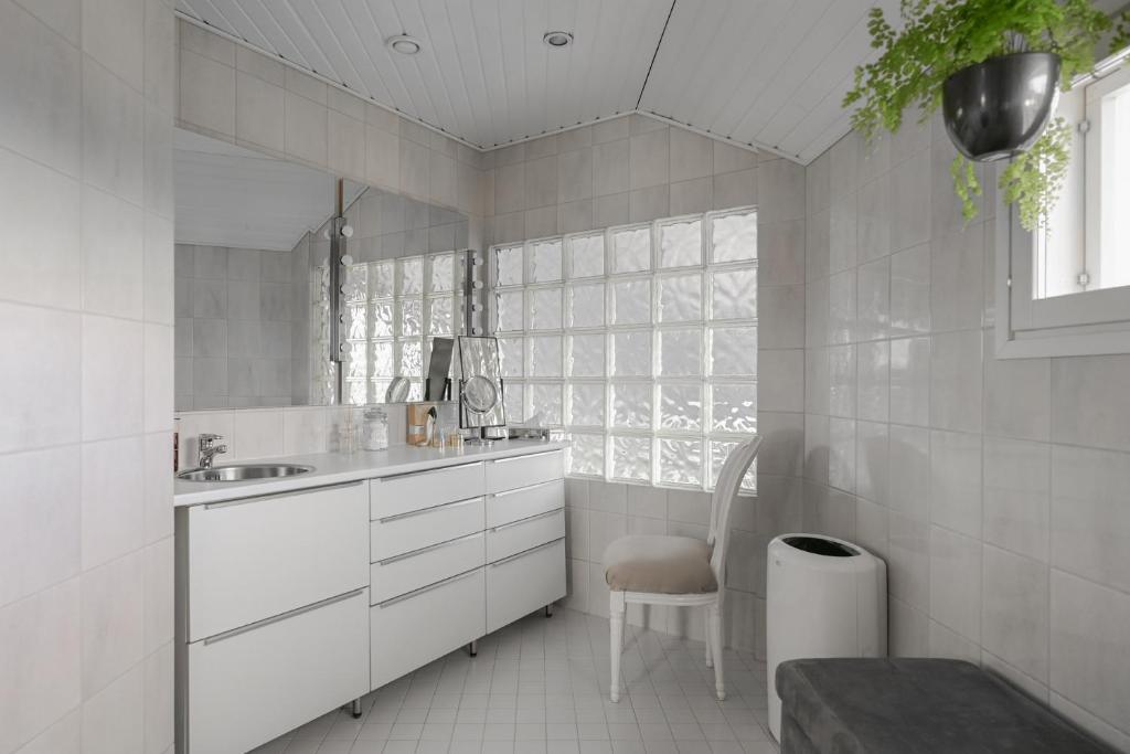 a white bathroom with a sink and a chair at Villa Lumikontupa in Jyväskylä