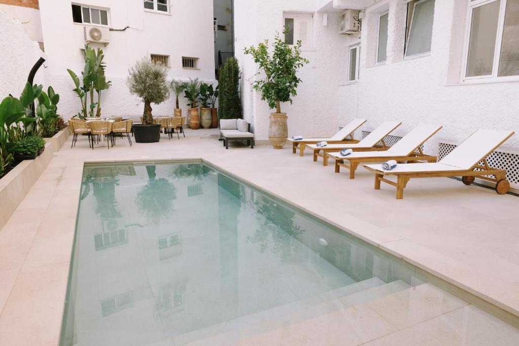 多列毛利诺斯Apartamentos Buendia Suites - Torremolinos Centro的庭院内一个带躺椅和桌子的游泳池