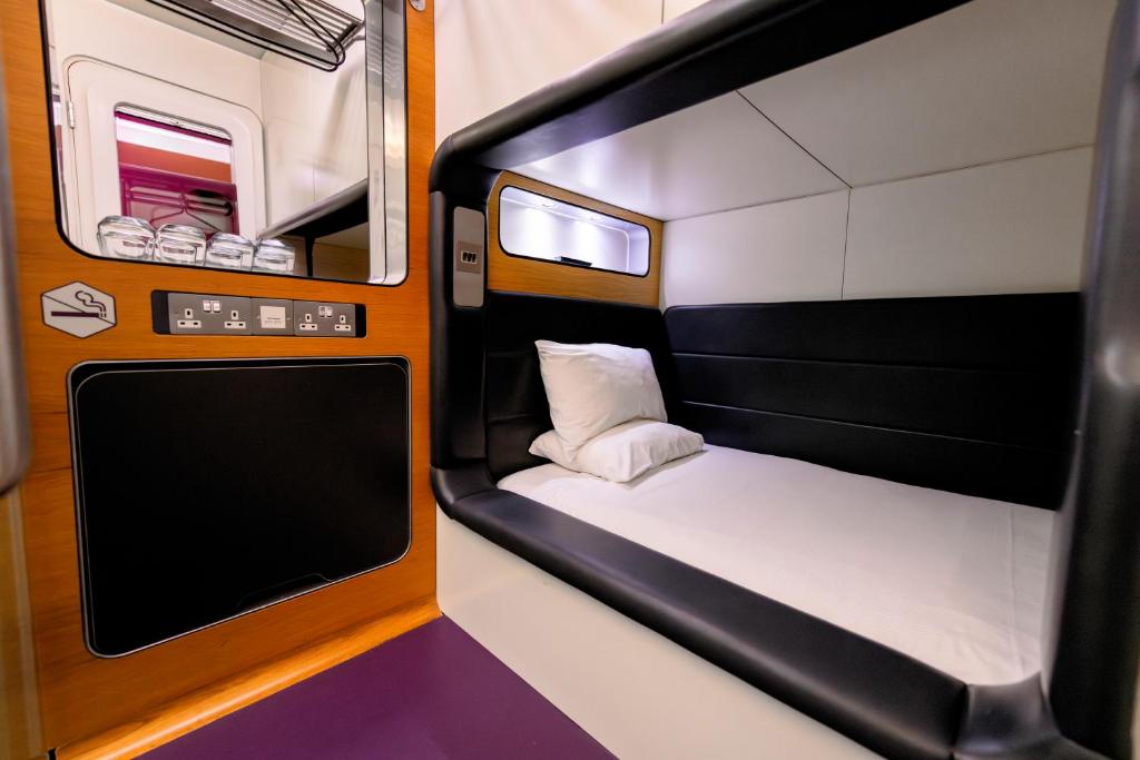 Una pequeña habitación de tren con una cama y una ventana. en YOTELAIR London Gatwick Airport, en Horley