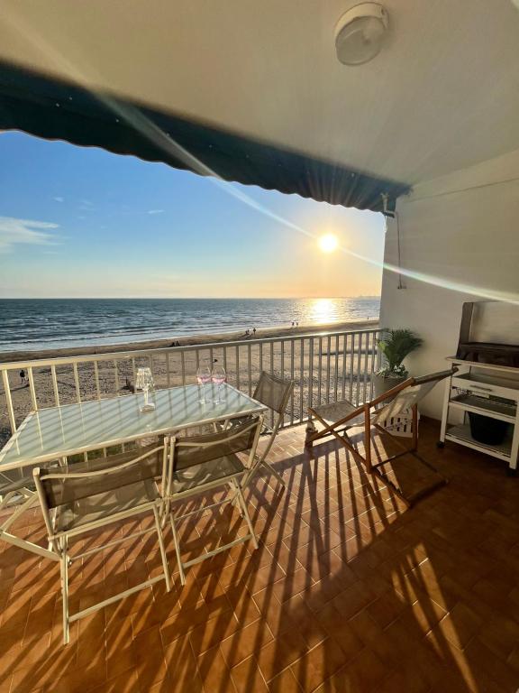 un balcon avec une table et une vue sur l'océan dans l'établissement Le Grau du Roi appartement première ligne en face de la mer, au Grau-du-Roi