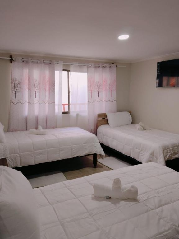 a room with three beds with white sheets at Hotel Victoria in Iquique