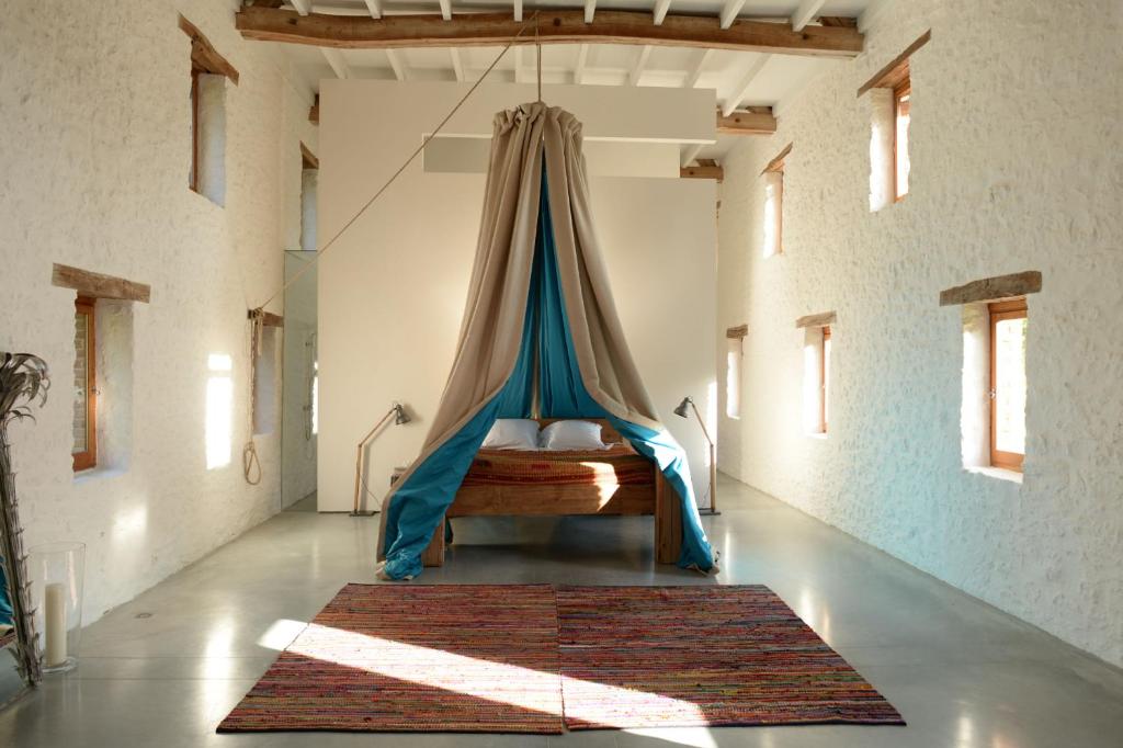 - une chambre avec un lit à baldaquin bleu dans l'établissement Les Bories - Loft in nature, à Urval