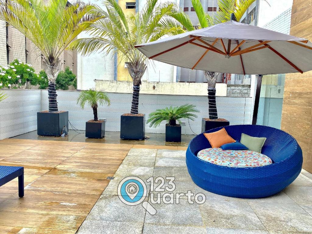 a blue chair with an umbrella and palm trees at Gold Flat Cabo Branco By 123Quarto Hospedagem in Tambaú