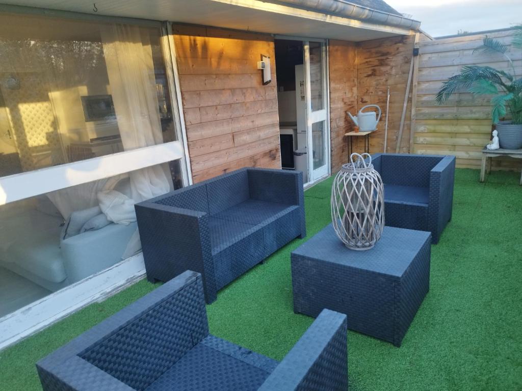 une terrasse avec des chaises bleues et un vase sur l'herbe. dans l'établissement Comme à la maison, à Cherbourg en Cotentin