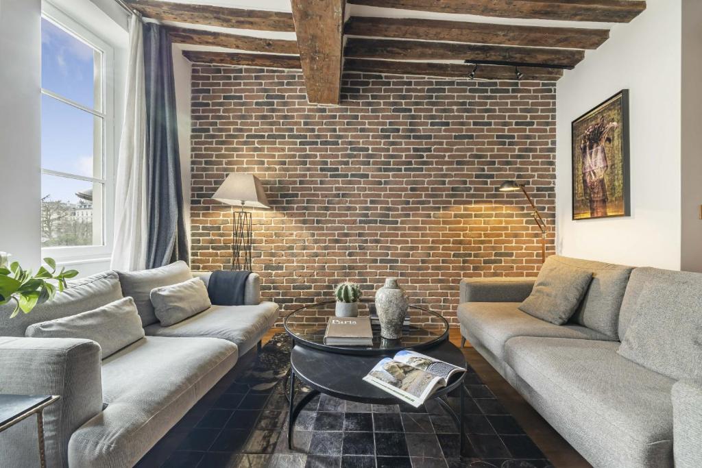 una sala de estar con 2 sofás y una pared de ladrillo en Ghost, en París