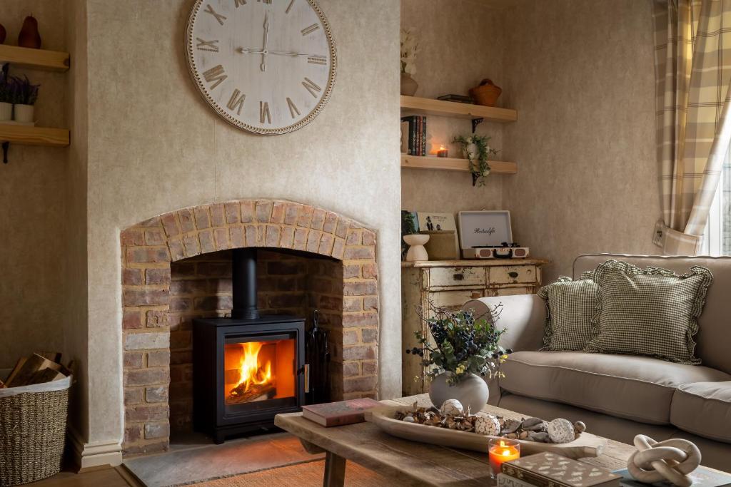 een woonkamer met een open haard en een klok aan de muur bij Broadway Country Chic Cottage in Broadway