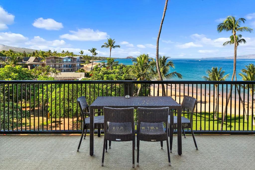 Una mesa y sillas en un balcón con vista al mar. en Mana Kai 410, en Wailea