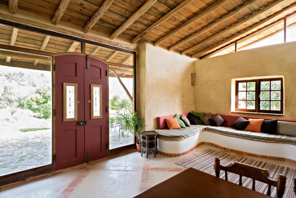 sala de estar con puerta roja y sofá en Quinta do Arade - casa 4 pétalas, en Barranco do Resgalho