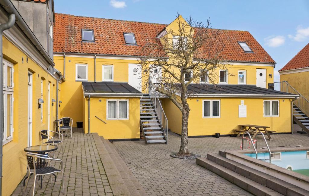 グドイェムにあるAmazing Apartment In Gudhjem With Wifiの中庭の木のある黄色い建物群