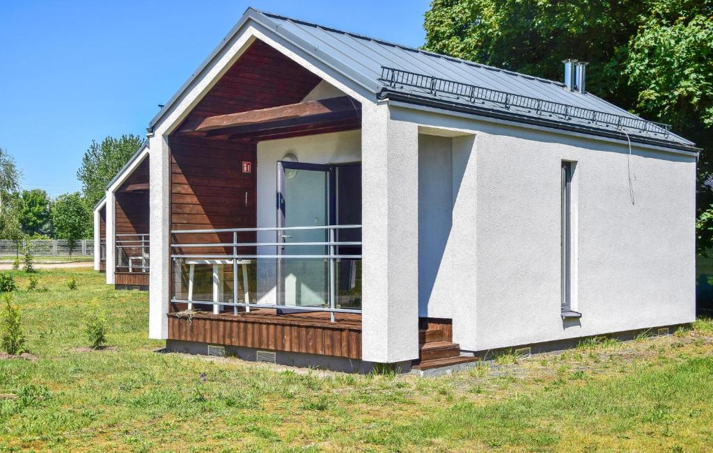 a small house with a balcony on a field at Nice Home In Nowe Warpno in Nowe Warpno