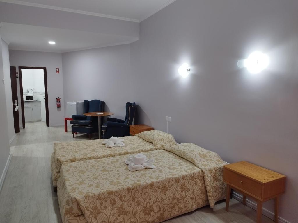 a bedroom with a bed and chairs and a table at Alojamento Central II in Funchal