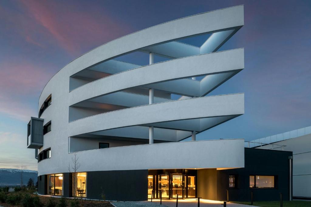 un grand bâtiment blanc avec beaucoup de fenêtres dans l'établissement AC Hotel by Marriott Saint-Julien-en-Genevois, à Saint-Julien-en-Genevois