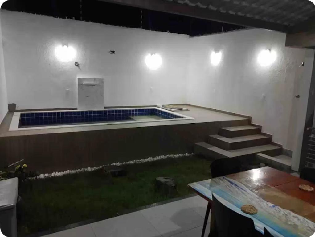 a room with a pool with stairs and a table at Casa Amar in Barra dos Coqueiros