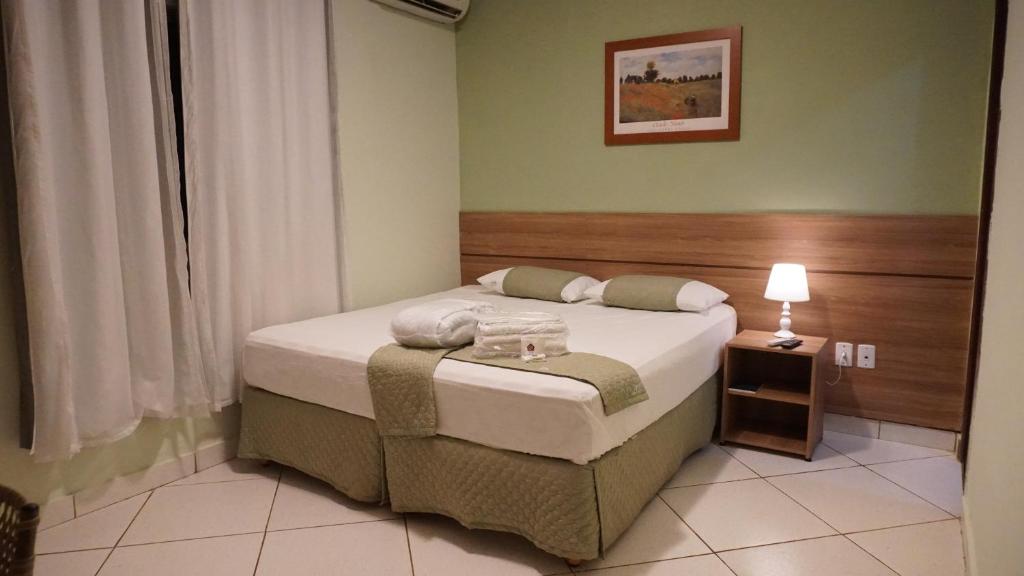 a bedroom with a bed and a lamp in it at Domus Hotel Torre - Canaã dos Carajás in Canaã dos Carajás