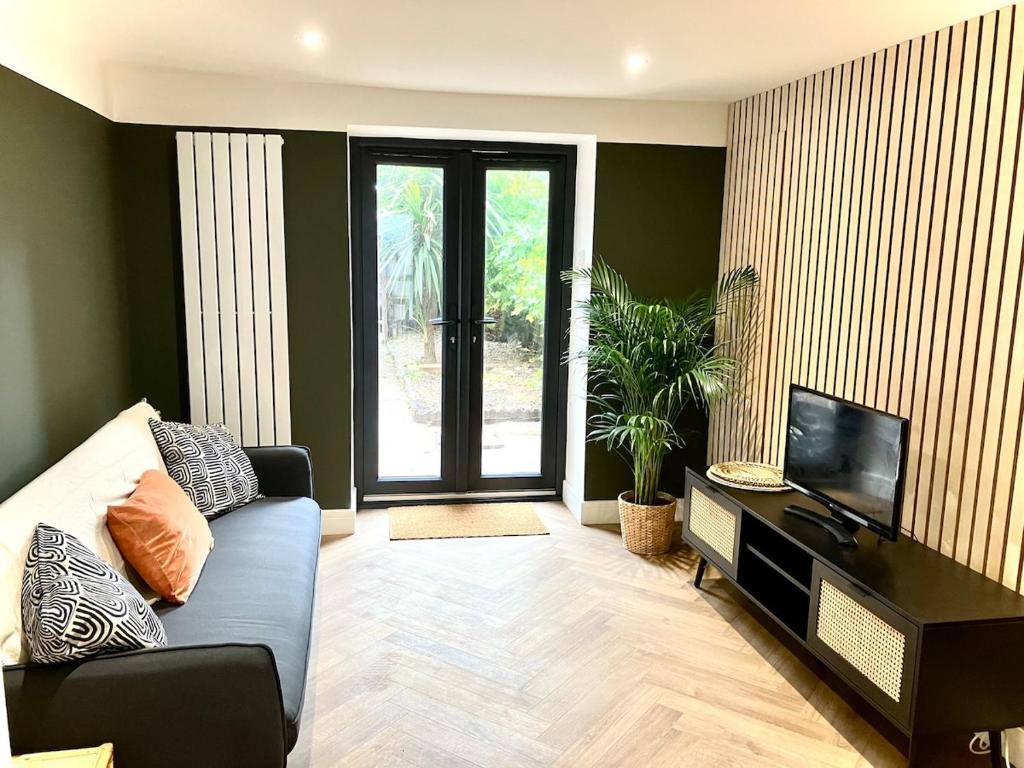 a living room with a couch and a television at City Centre Garden Apartment in Exeter