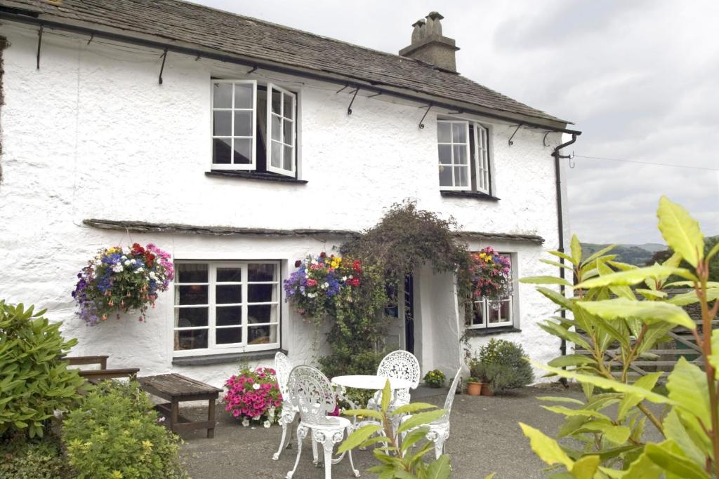 a white house with a table and chairs and flowers at High Wray Farm in Ambleside
