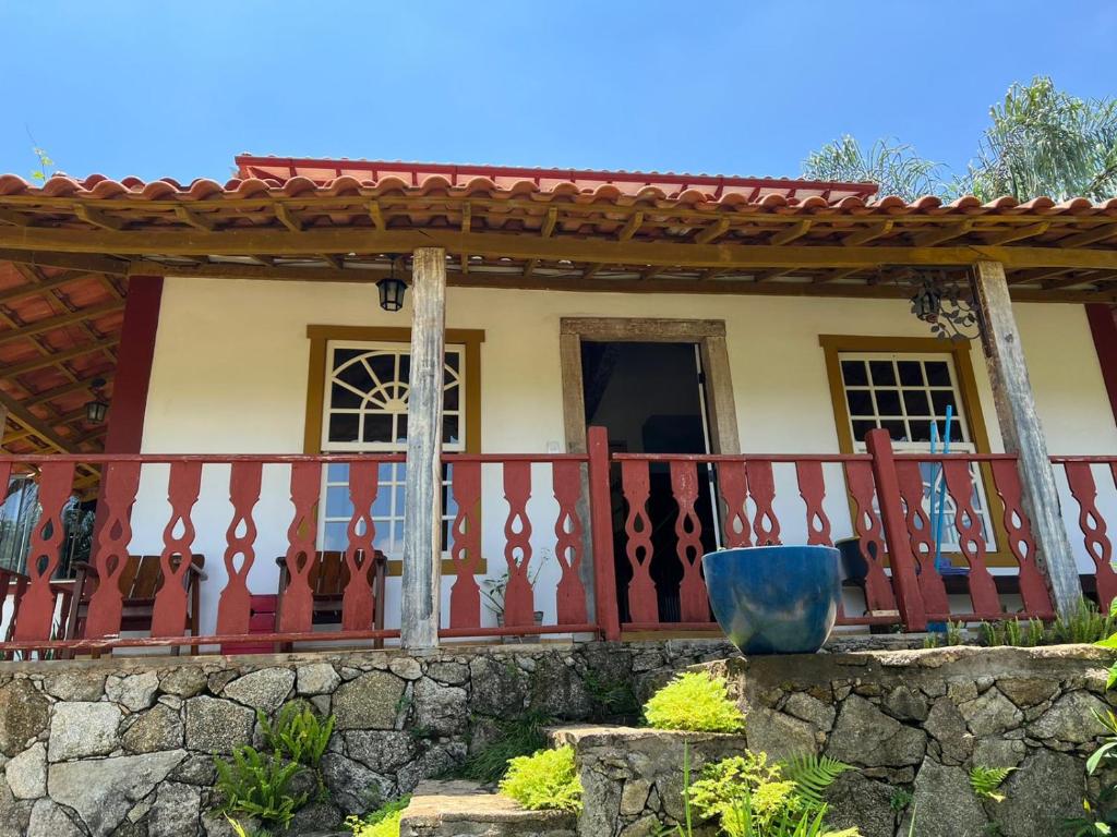 a house with a red fence and a stone wall at CASA POR do SOL in Tiradentes