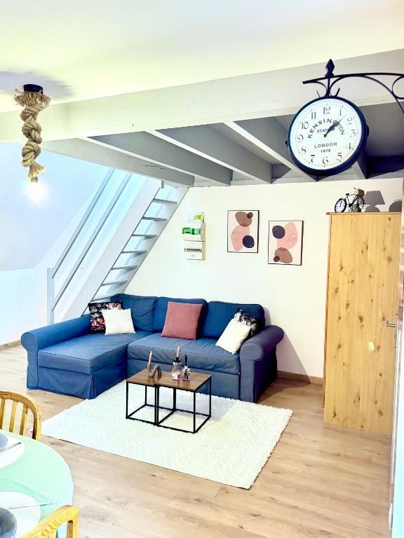 un salon avec un canapé bleu et un réveil dans l'établissement Escale du mont, à Pontorson