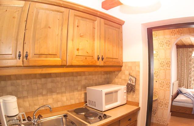 eine Küche mit Holzschränken und einer Mikrowelle auf der Theke in der Unterkunft Haus Rosswiese in Strobl