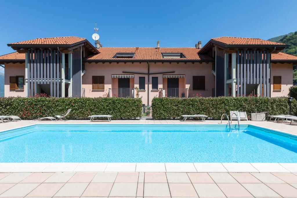 a villa with a swimming pool in front of a house at Modern apartment with balcony-garage-and pool in Bellano