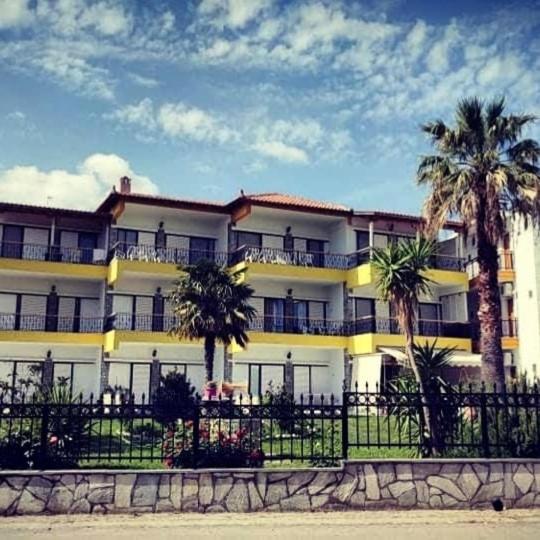 a large building with palm trees in front of it at Villa Christina Sea Side A in Hanioti
