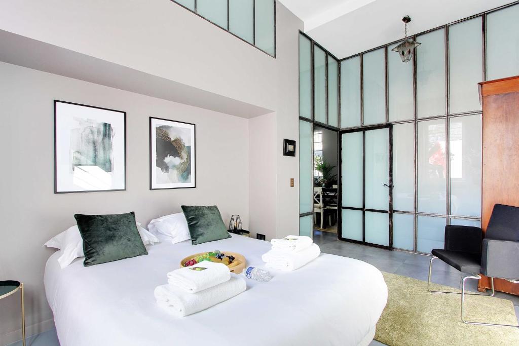 une chambre avec un lit blanc avec des serviettes dessus dans l'établissement Magnificent apartment - 2BR 7P - Buttes Chaumont, à Paris