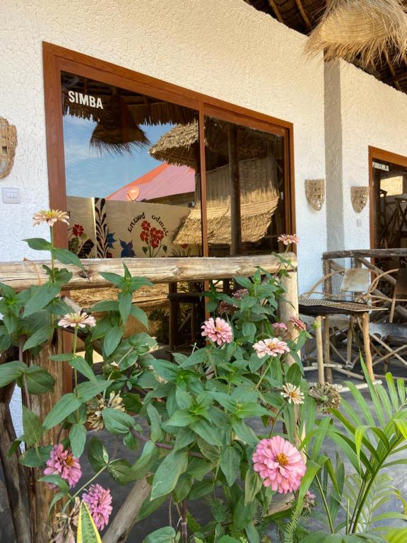 a window of a restaurant with flowers in front of it at Bougainvillea nungwi zanzibar in Nungwi