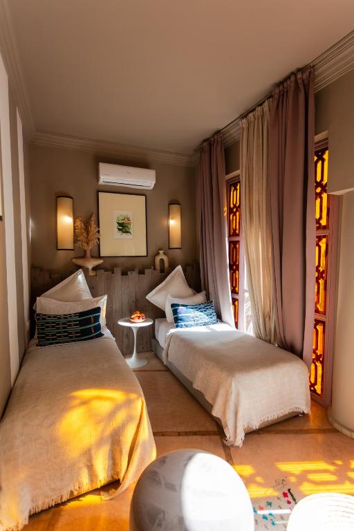 deux lits assis dans une pièce avec fenêtres dans l'établissement Riad 117, à Marrakech
