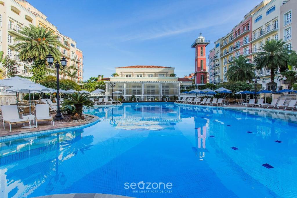 a large swimming pool in a city with buildings at Charmosos Studios no IL Campanario Villaggio Resort ILCJR II in Florianópolis
