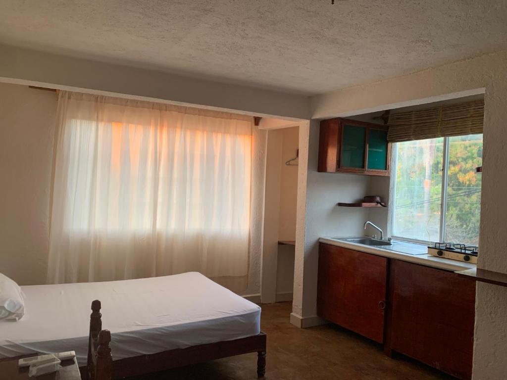 ein Schlafzimmer mit einem Bett, einem Waschbecken und einem Fenster in der Unterkunft Habitaciones Nava in Brisas de Zicatela
