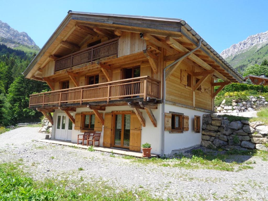 une maison en rondins dans les montagnes avec un balcon dans l'établissement La Bartavelle, à La Giettaz