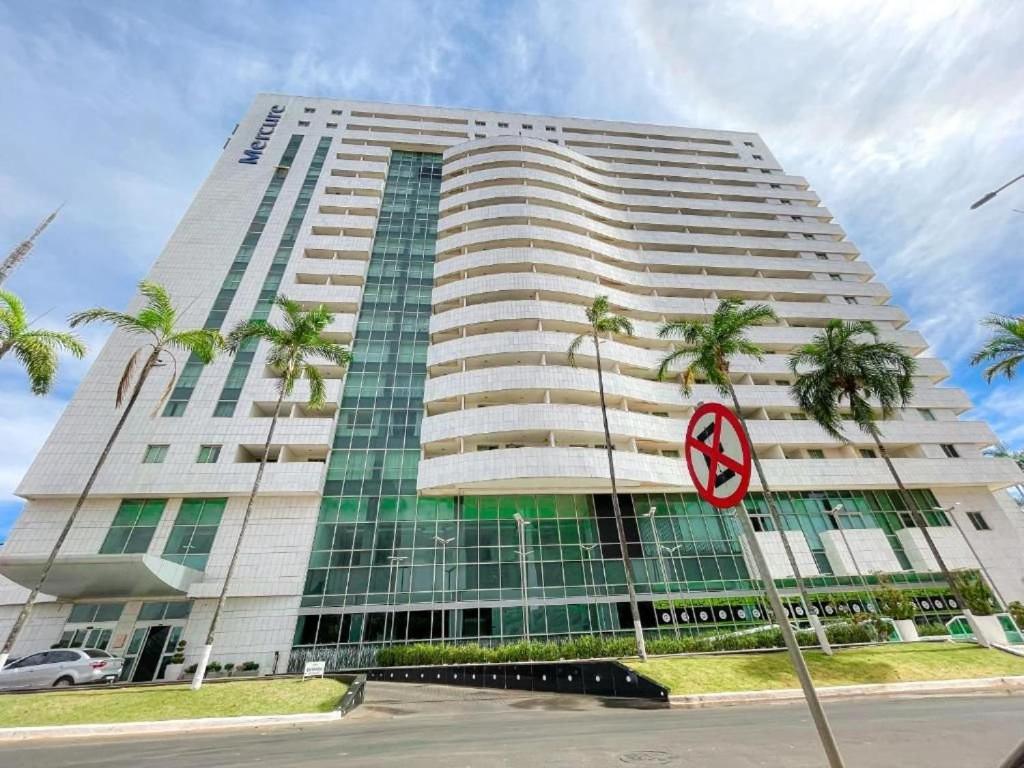 a tall building with palm trees in front of it at Flat moderno Hotel Mercure Líder in Brasilia