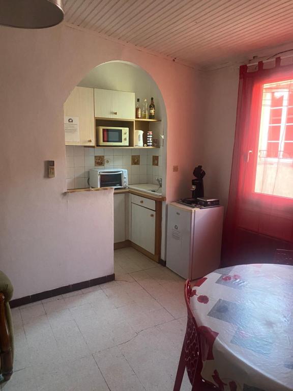 a small kitchen with a table and a window at Gîte climatisé proche lac et Mer avec accès jacuzzi en sus in Vauvert