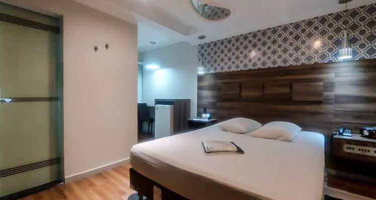 a bedroom with a large white bed with a wooden headboard at Motel Makakus in Sao Paulo