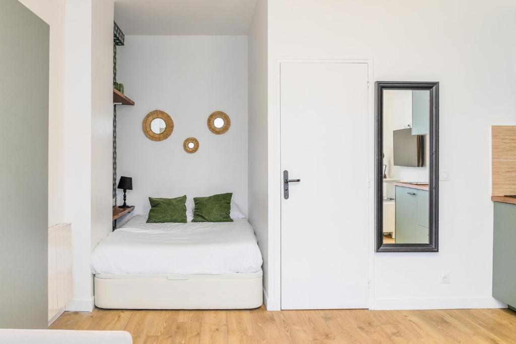 Cette chambre blanche comprend un lit et un miroir. dans l'établissement Enjoy in a Lovely Nest with modern design, à Paris