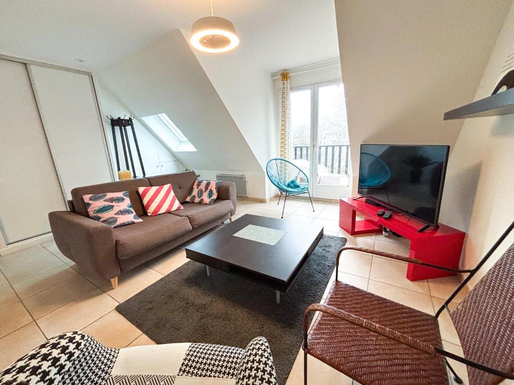 a living room with a couch and a flat screen tv at Les diablotines - 6 couchages 2 sdb - proche plage in Cabourg