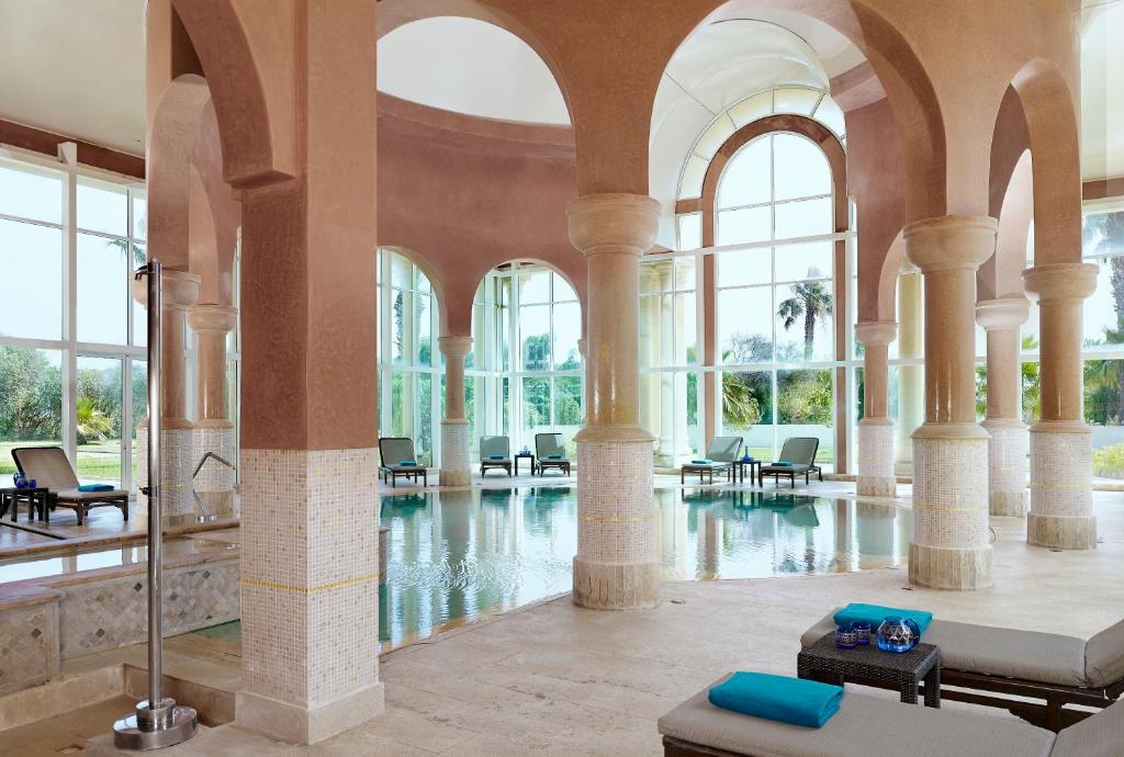a large lobby with a pool with chairs and windows at The Residence Tunis in Gammarth