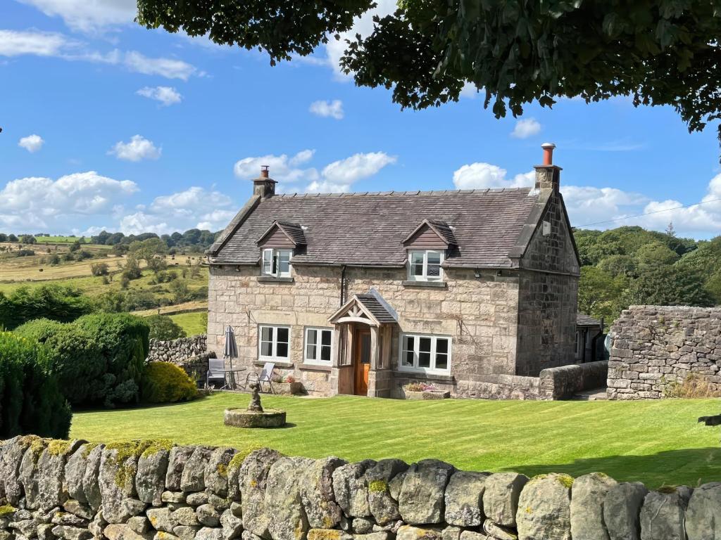 an old stone house with a stone wall at Sycamore Cottage in Ashbourne