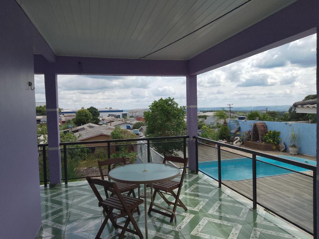a balcony with a table and chairs and a pool at Pousada Oliveira in Ametista do Sul