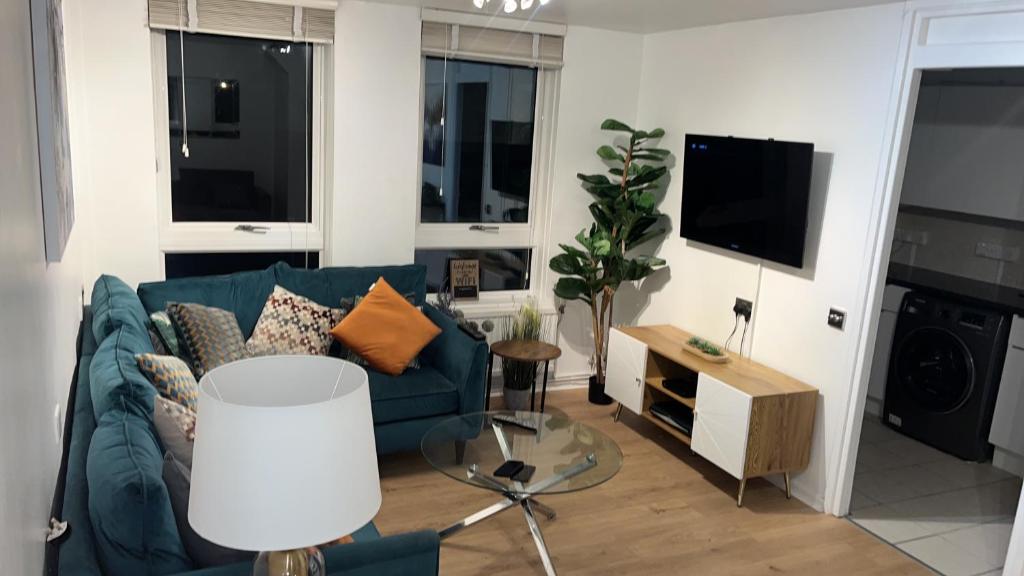 een woonkamer met een blauwe bank en een tv bij Apartment facing Covent Garden station in Londen