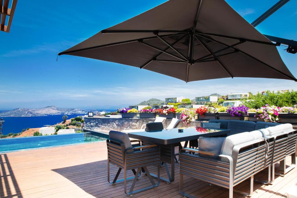 a patio with a table and chairs and an umbrella at Villa Calista by Important Group Travel in Yalıkavak