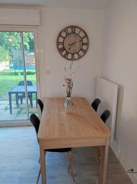 a dining room table with chairs and a clock on the wall at Ty Moon in Lannion