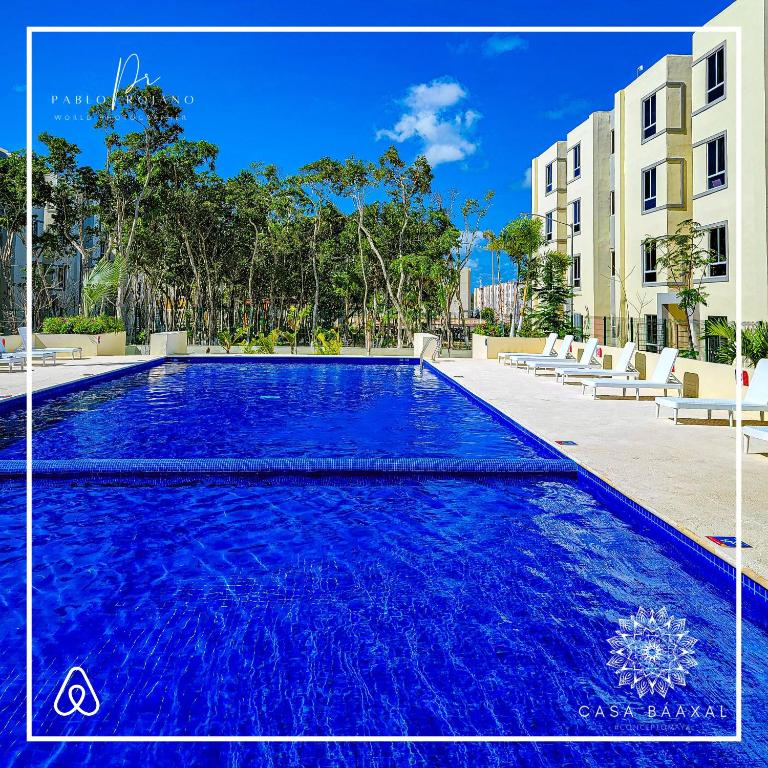 a large blue swimming pool in front of a building at Casa Baaxal in Tulum
