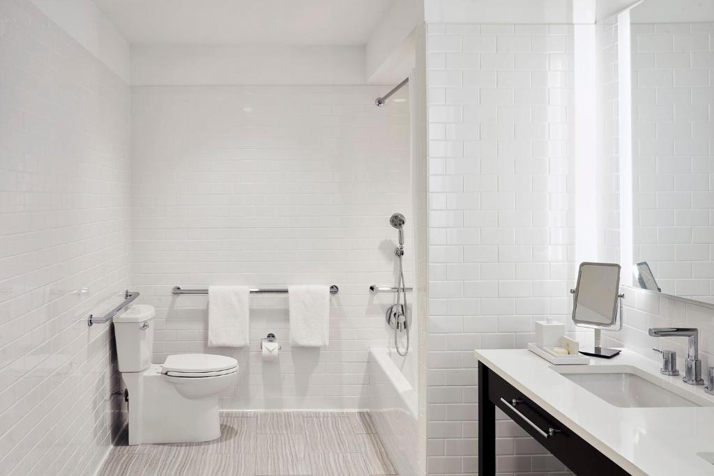 a white bathroom with a toilet and a sink at Isla Bella Beach Resort & Spa - Florida Keys in Marathon
