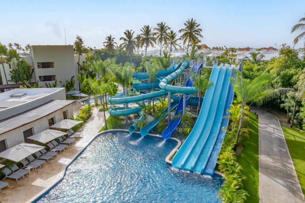 Water slides and pool area with loungers, lush landscaping, and hotel buildings.