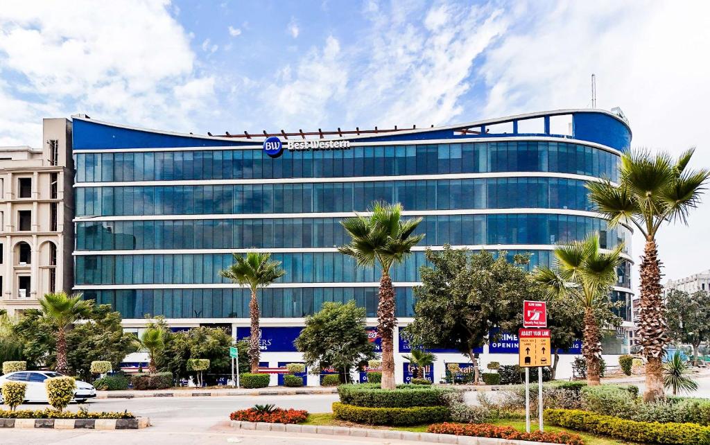 a large glass building with palm trees in front of it at Best Western Hotel Rawalpindi Central in Rawalpindi